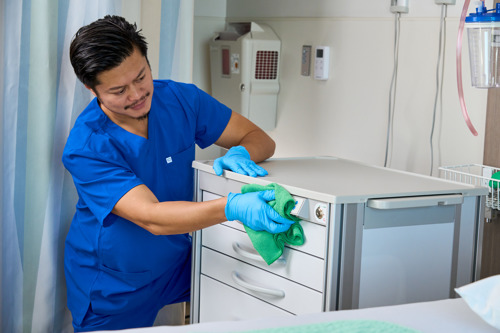 Person cleaning with green microfibre cloth
